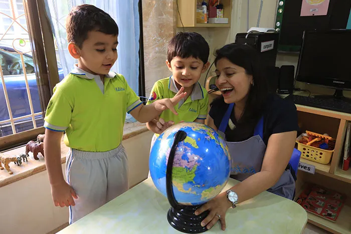 Kindergarten children exploring a globe with their teacher at Edistää Preschool, Wadala West, Mumbai